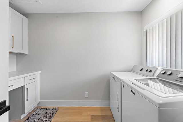 laundry area featuring cabinets, washer and dryer, and light wood-type flooring