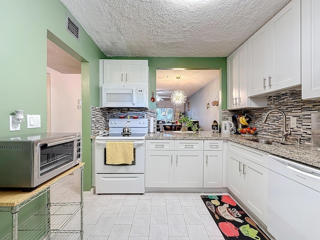 kitchen with sink, white cabinetry, hanging light fixtures, a notable chandelier, and white appliances