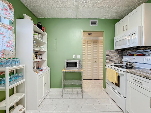 kitchen with tasteful backsplash, light tile patterned floors, white cabinets, and white appliances