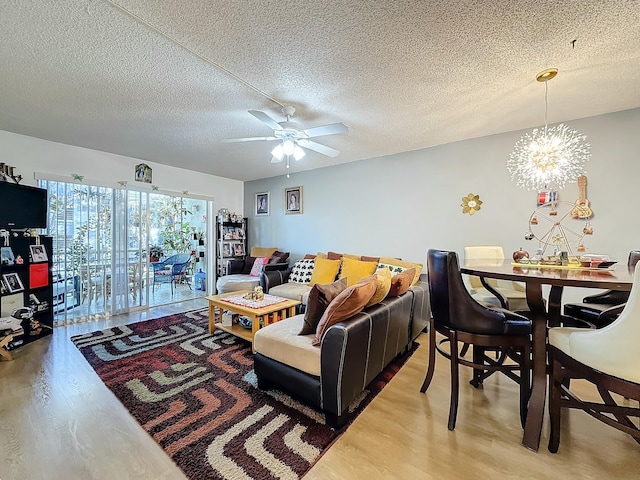 living room with ceiling fan with notable chandelier, hardwood / wood-style floors, and a textured ceiling