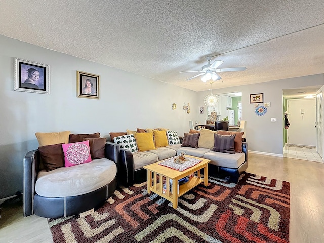 living room with ceiling fan, a textured ceiling, and light wood-type flooring