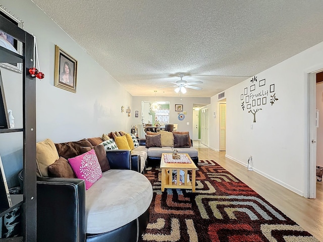 living room with ceiling fan, wood-type flooring, and a textured ceiling