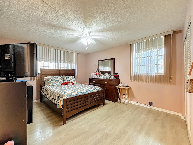 bedroom featuring multiple windows, ceiling fan, light hardwood / wood-style floors, and a textured ceiling