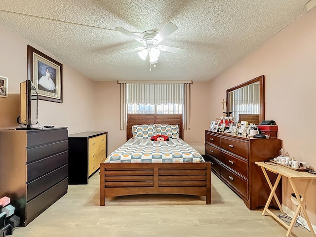 bedroom featuring ceiling fan, a textured ceiling, and light hardwood / wood-style floors