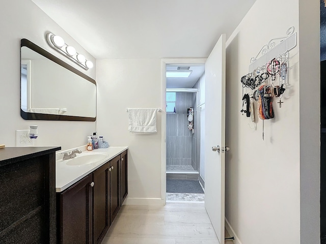 bathroom featuring vanity, hardwood / wood-style floors, and tiled shower