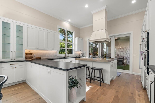 kitchen featuring white cabinetry, tasteful backsplash, light hardwood / wood-style floors, and a breakfast bar area