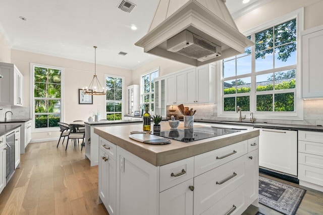 kitchen with dishwasher, white cabinets, a kitchen island, black electric cooktop, and decorative light fixtures