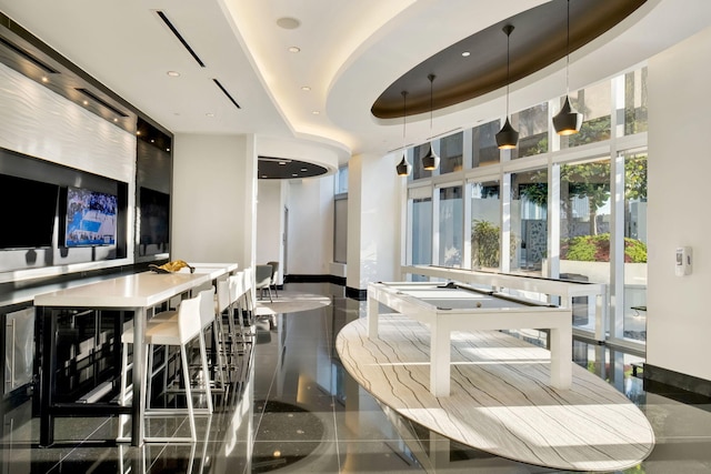 interior space with decorative light fixtures, a raised ceiling, and a high ceiling