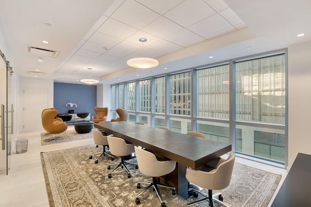 dining space featuring expansive windows, a paneled ceiling, a tray ceiling, and a barn door