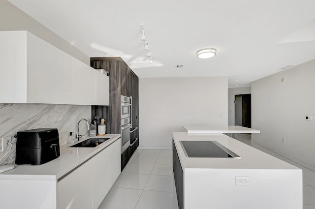 kitchen with black electric cooktop, sink, a center island, and white cabinets