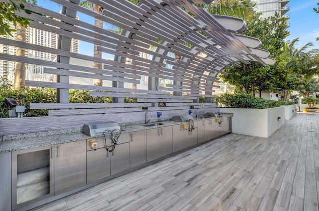 wooden terrace featuring area for grilling, sink, a pergola, and grilling area