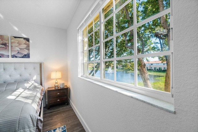 bedroom featuring wood-type flooring and a water view