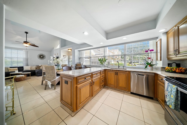 kitchen featuring light tile patterned floors, a tray ceiling, stainless steel appliances, and kitchen peninsula