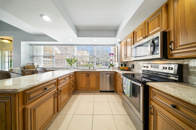 kitchen featuring tasteful backsplash, appliances with stainless steel finishes, a tray ceiling, and kitchen peninsula