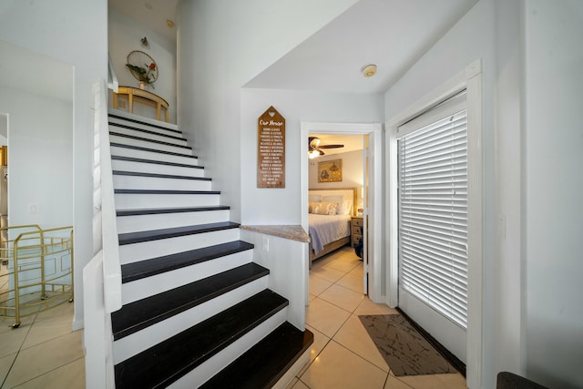 stairway with ceiling fan and tile patterned flooring