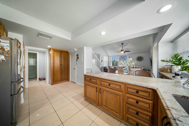 kitchen featuring light tile patterned flooring, light stone countertops, stainless steel fridge, and ceiling fan