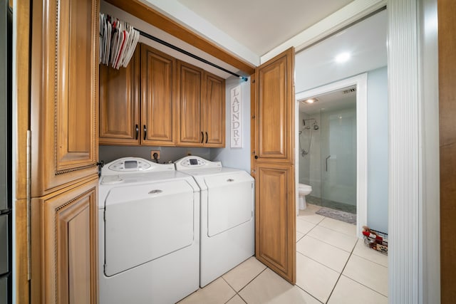 clothes washing area with cabinets, separate washer and dryer, and light tile patterned floors