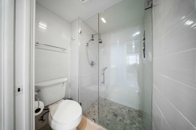 bathroom featuring walk in shower, toilet, and tile walls