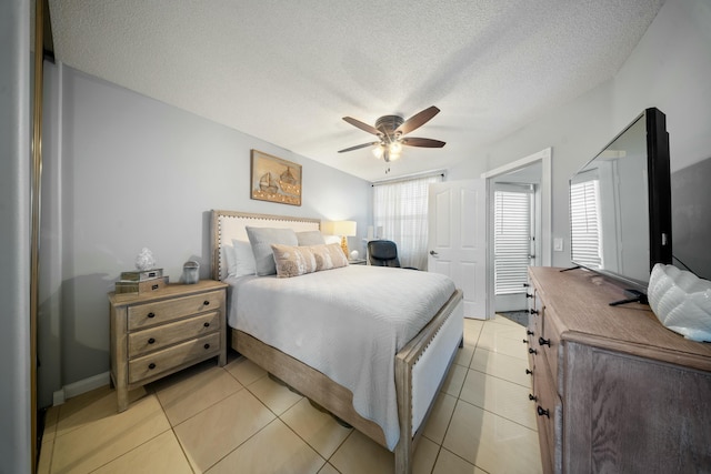 tiled bedroom with ceiling fan and a textured ceiling