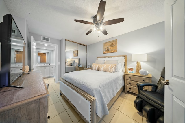 tiled bedroom featuring ceiling fan, a textured ceiling, and ensuite bathroom