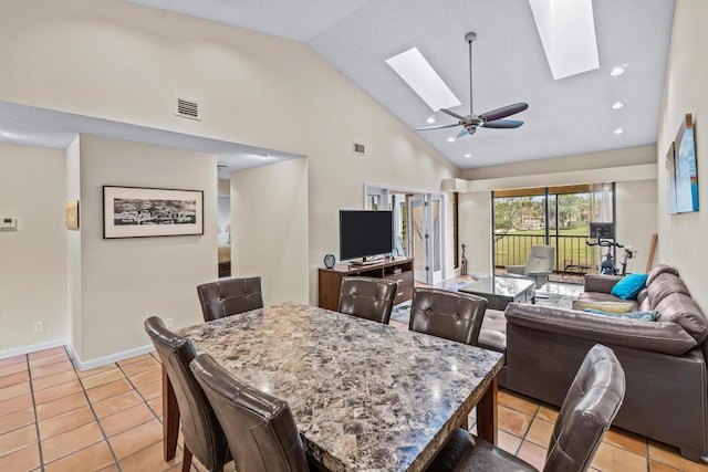 tiled dining room with ceiling fan, a skylight, and high vaulted ceiling