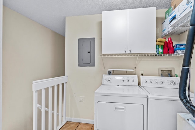 clothes washing area with washing machine and clothes dryer, light tile patterned floors, electric panel, and a textured ceiling