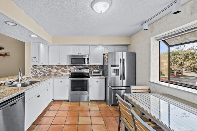 kitchen featuring appliances with stainless steel finishes, sink, backsplash, white cabinets, and light stone counters