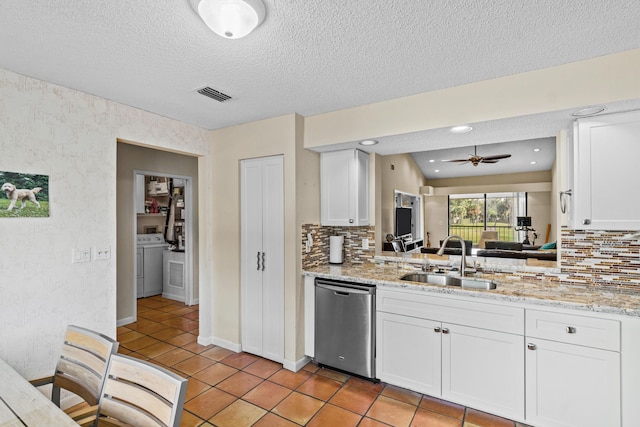 kitchen with white cabinetry, dishwasher, sink, washer / dryer, and light stone countertops