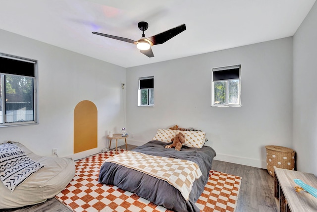 bedroom with multiple windows, ceiling fan, and light hardwood / wood-style floors