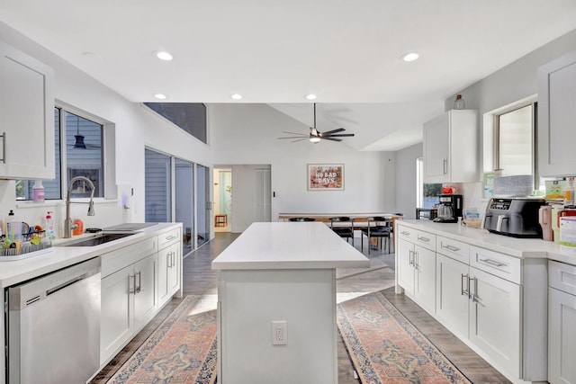 kitchen featuring a kitchen island, white cabinetry, sink, stainless steel dishwasher, and ceiling fan