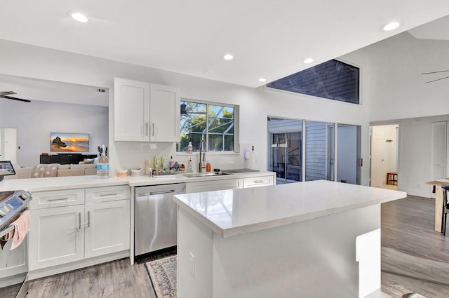 kitchen with appliances with stainless steel finishes, white cabinetry, sink, a center island, and light hardwood / wood-style floors