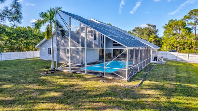 back of property with a fenced in pool, a yard, and glass enclosure