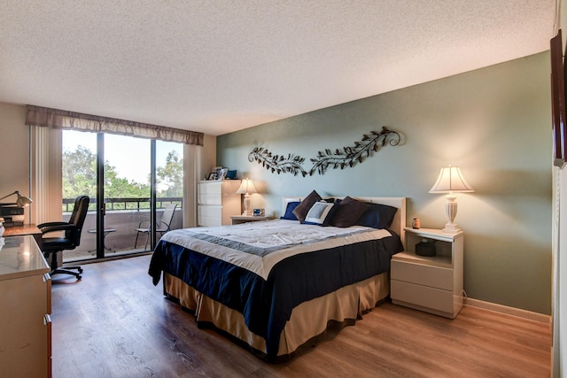 bedroom featuring access to exterior, hardwood / wood-style floors, and a textured ceiling