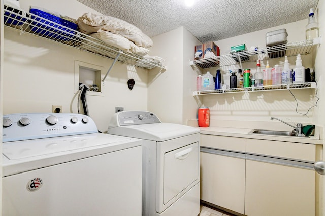 laundry area featuring washer and clothes dryer, sink, and a textured ceiling