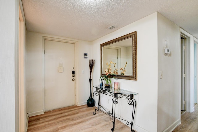 hall featuring light hardwood / wood-style flooring and a textured ceiling