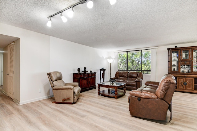 living room with track lighting, a textured ceiling, and light hardwood / wood-style flooring