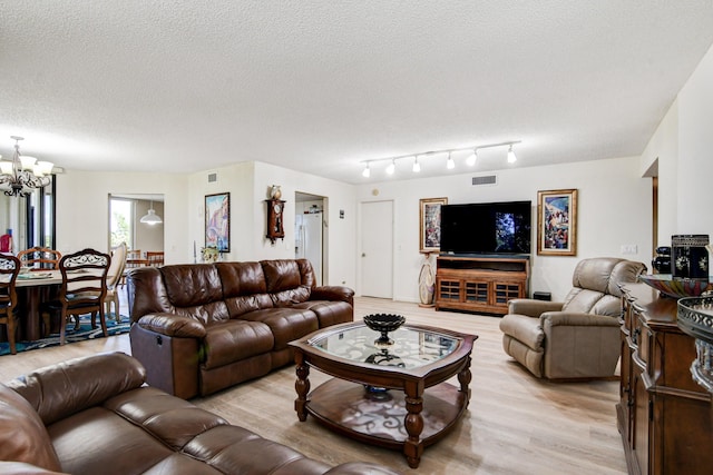 living room featuring light wood-type flooring, a notable chandelier, and a textured ceiling