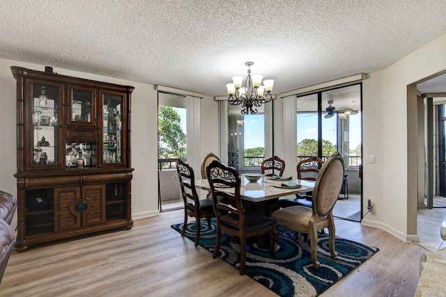 dining space with an inviting chandelier, a wealth of natural light, a textured ceiling, and light wood-type flooring