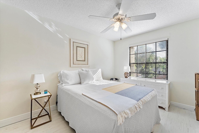 bedroom featuring ceiling fan, light hardwood / wood-style floors, and a textured ceiling