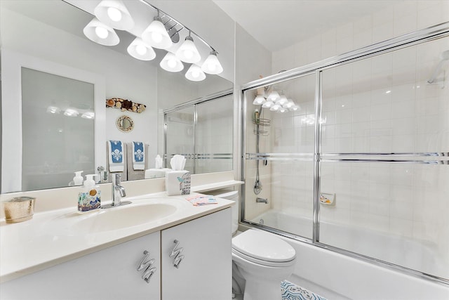 full bathroom with enclosed tub / shower combo, vanity, and toilet