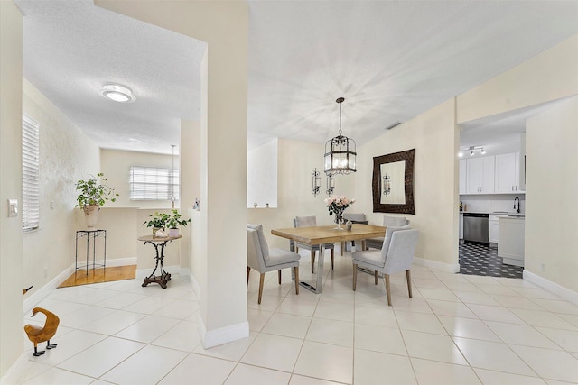 dining space featuring sink, a notable chandelier, a textured ceiling, and light tile patterned flooring