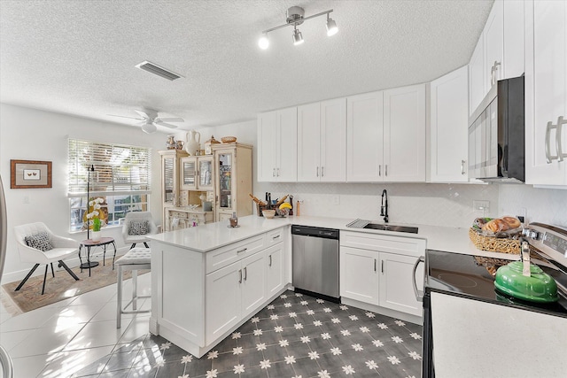 kitchen with sink, white cabinets, a kitchen bar, kitchen peninsula, and stainless steel appliances