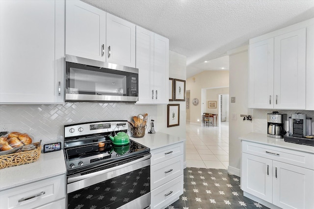 kitchen with lofted ceiling, white cabinetry, a textured ceiling, appliances with stainless steel finishes, and decorative backsplash