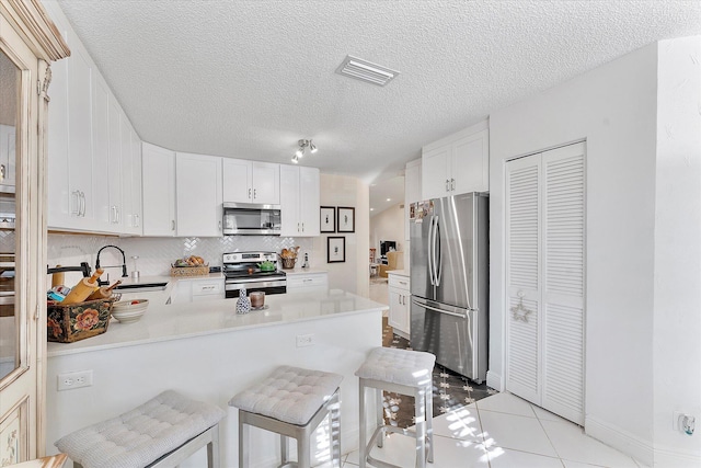 kitchen with a breakfast bar, sink, white cabinets, kitchen peninsula, and stainless steel appliances