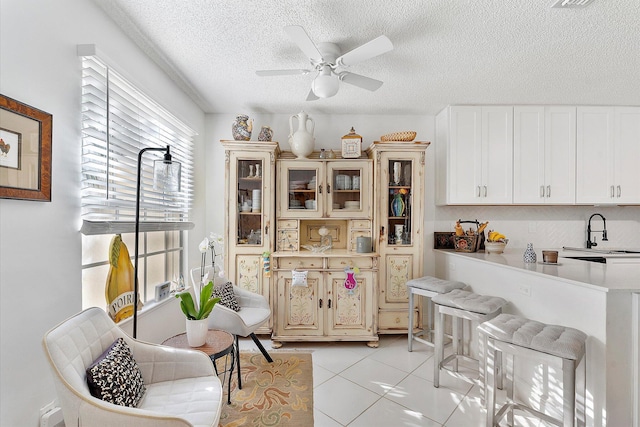 kitchen with light tile patterned flooring, sink, a textured ceiling, and ceiling fan