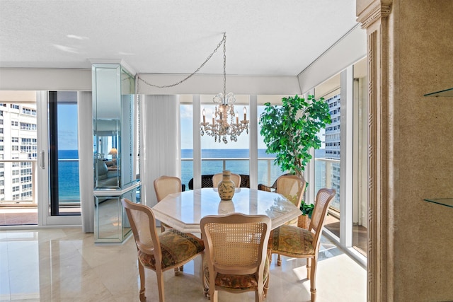 dining space featuring a water view, a textured ceiling, and an inviting chandelier