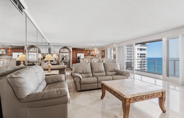 living room featuring a water view, a textured ceiling, and a chandelier