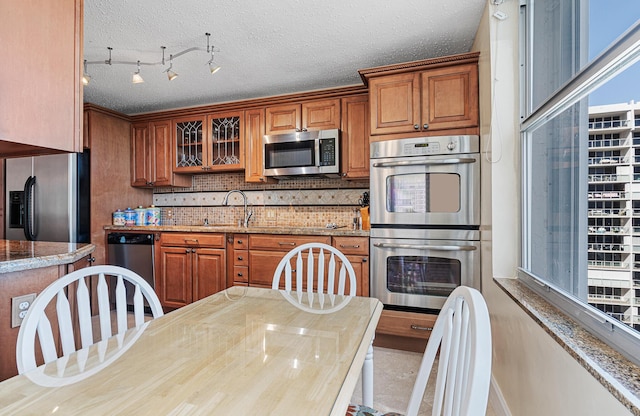 kitchen featuring backsplash, stainless steel appliances, and light stone countertops