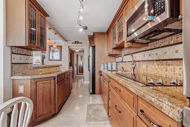 kitchen featuring stainless steel appliances, sink, light stone counters, and decorative light fixtures