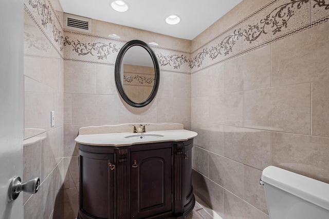 bathroom with tile walls, vanity, and toilet